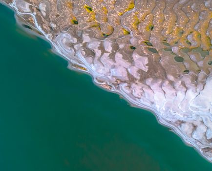 A captivating aerial view of intricate tidal patterns meeting the ocean shore.
