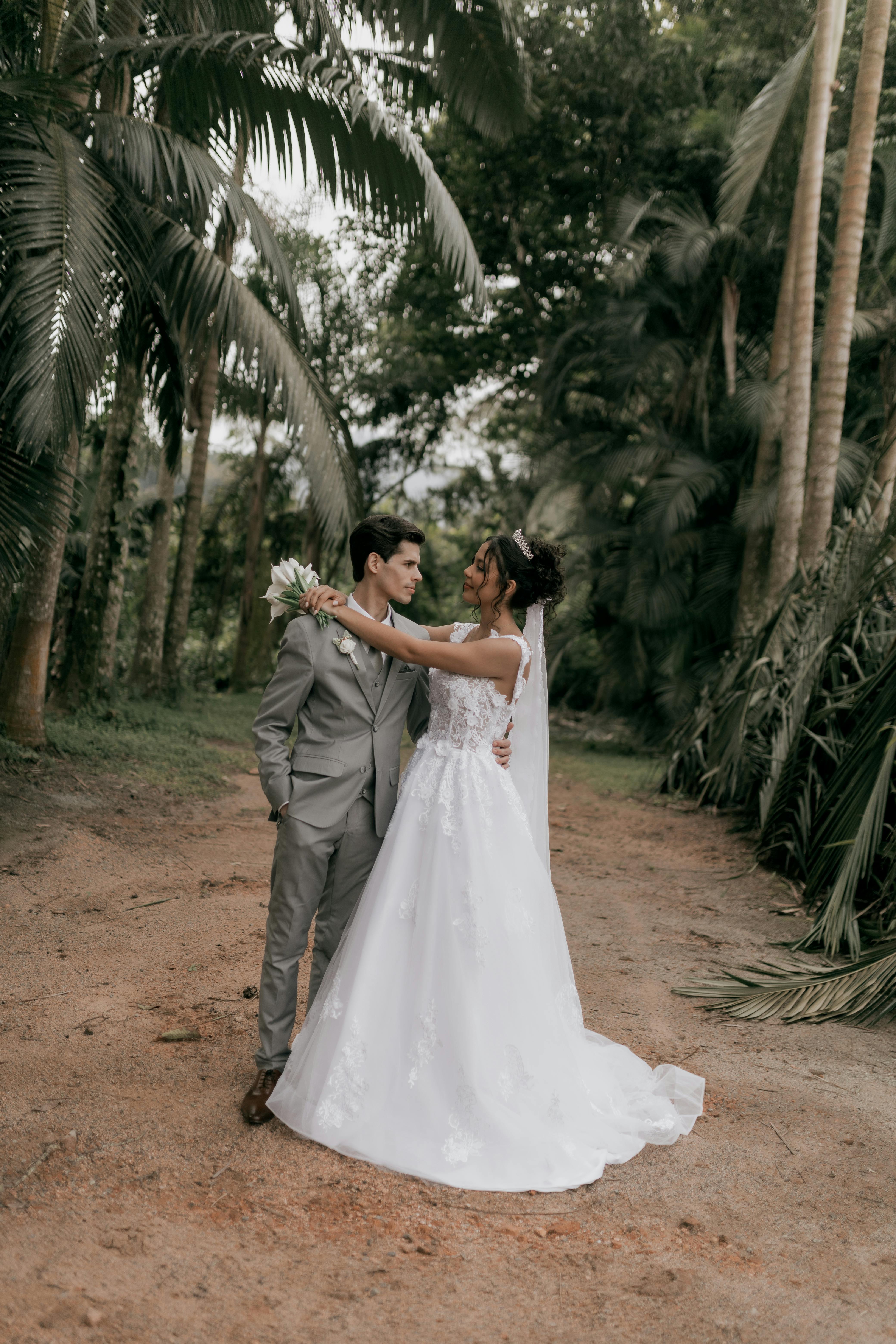 Bride and groom embrace in a lush tropical garden, capturing romance and elegance.