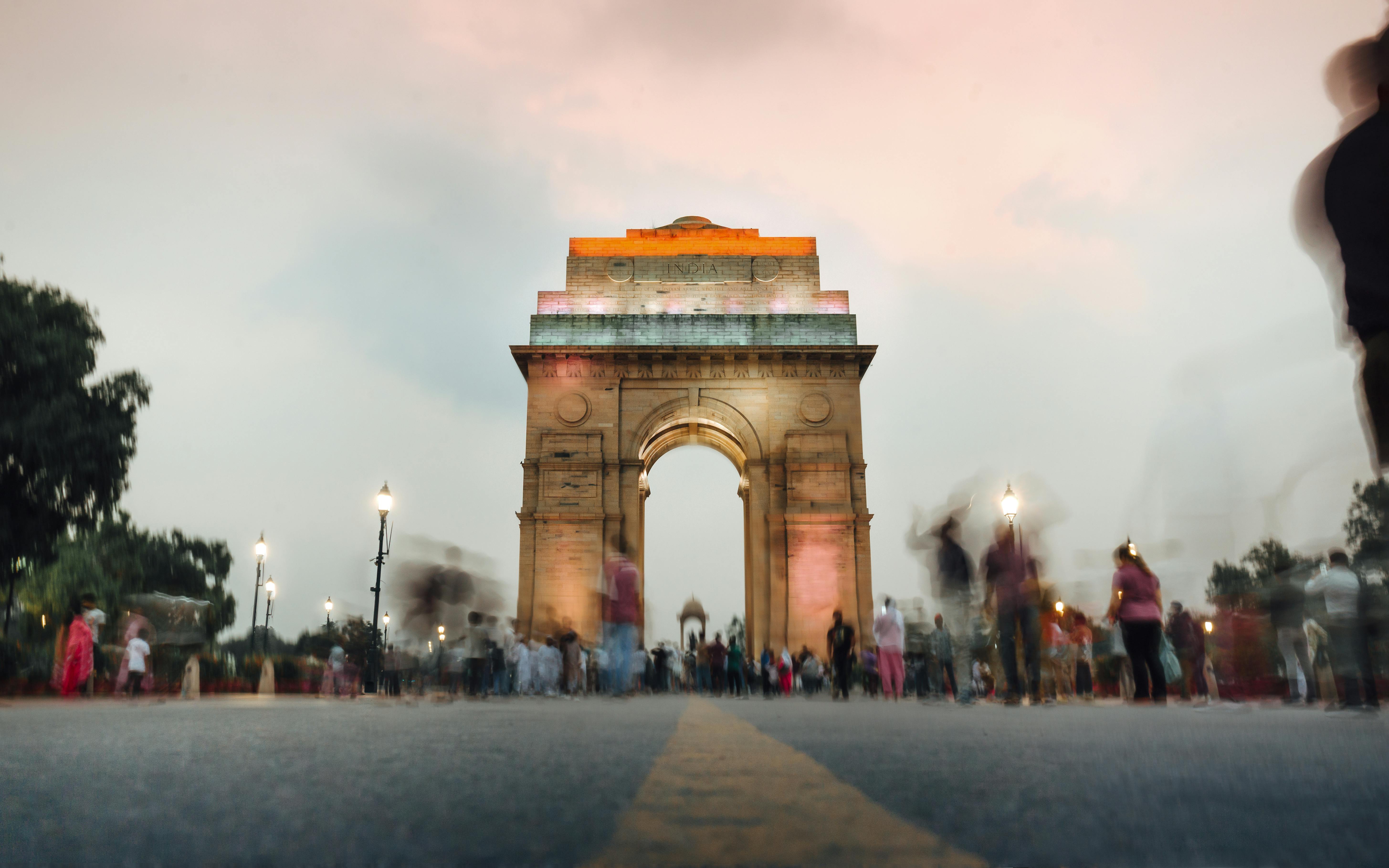Gratis Una vista mozzafiato dell'India Gate a Nuova Delhi al tramonto, con una folla dinamica. Foto a disposizione