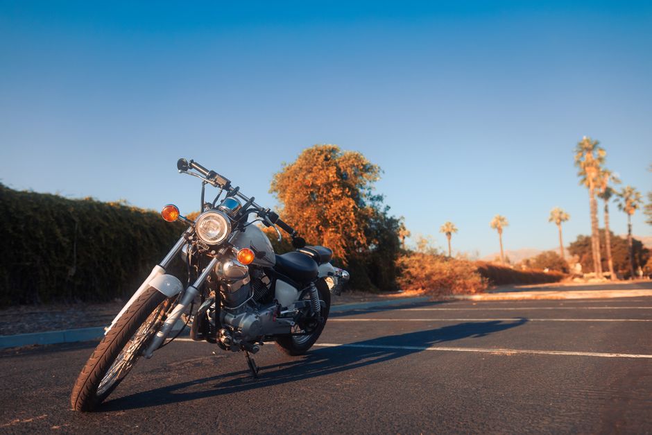 A classic cruiser motorcycle parked against a sunny backdrop with palm trees and clear skies, exuding a vintage vibe.
