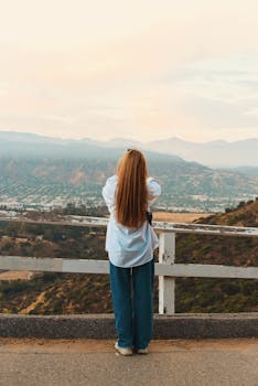A person stands overlooking the expansive Los Angeles landscape at sunrise, capturing the serene view.