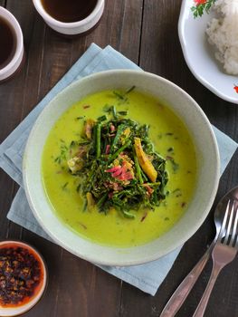 Delicious Indonesian vegetable curry served in a bowl with rice on a rustic wooden table.