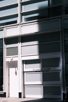 Modern building facade with 'No Parking Anytime' sign, featuring dramatic shadows.