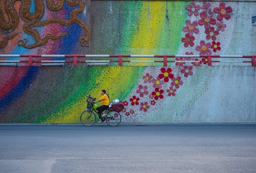 A person cycling past a colorful mural featuring flowers and abstract patterns.