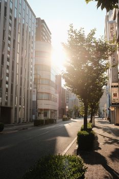 A serene city street at sunrise with modern buildings and trees, creating a peaceful urban atmosphere.