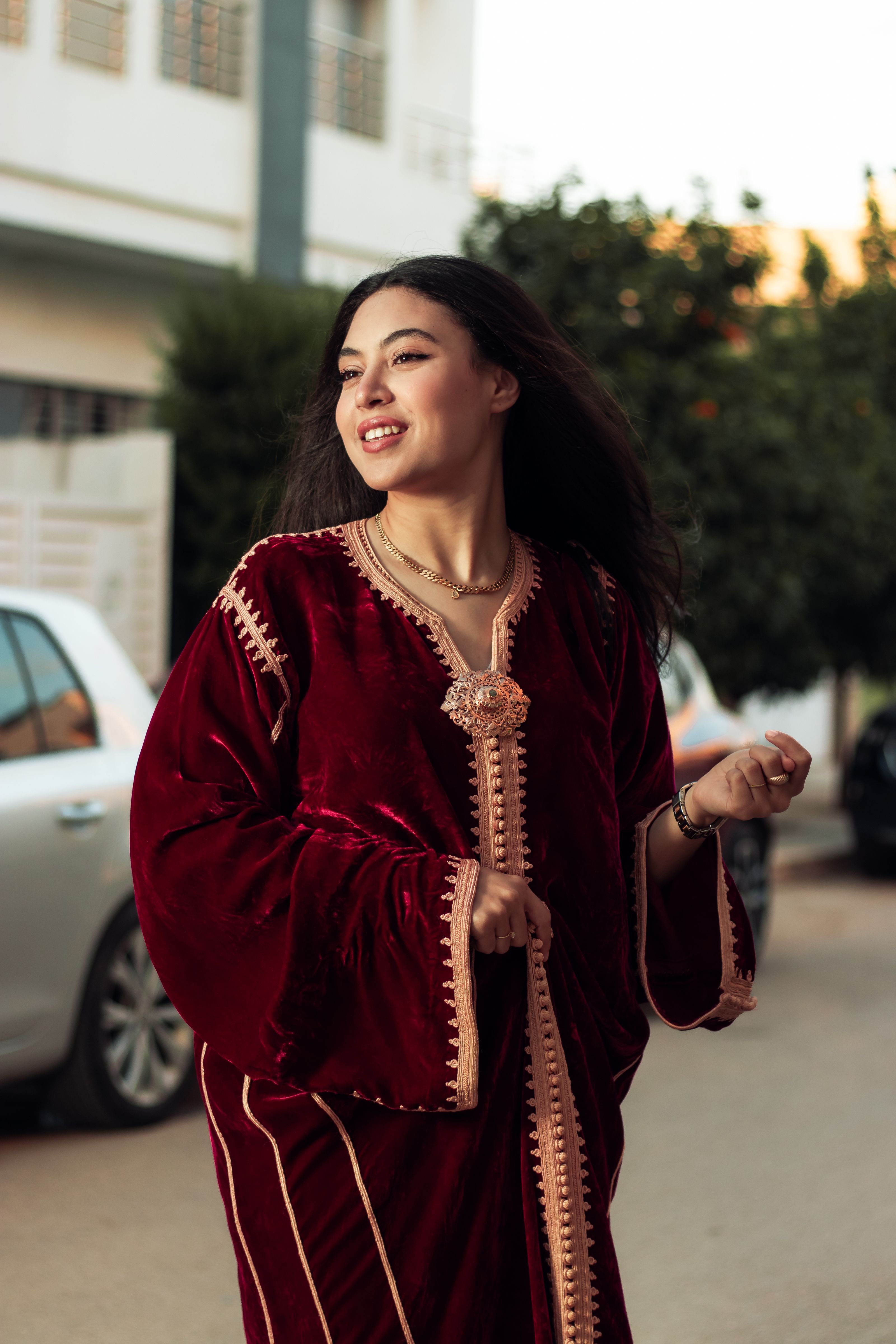 Jovem alegre vestindo um cafetã de veludo ao ar livre, exalando estilo e elegância.