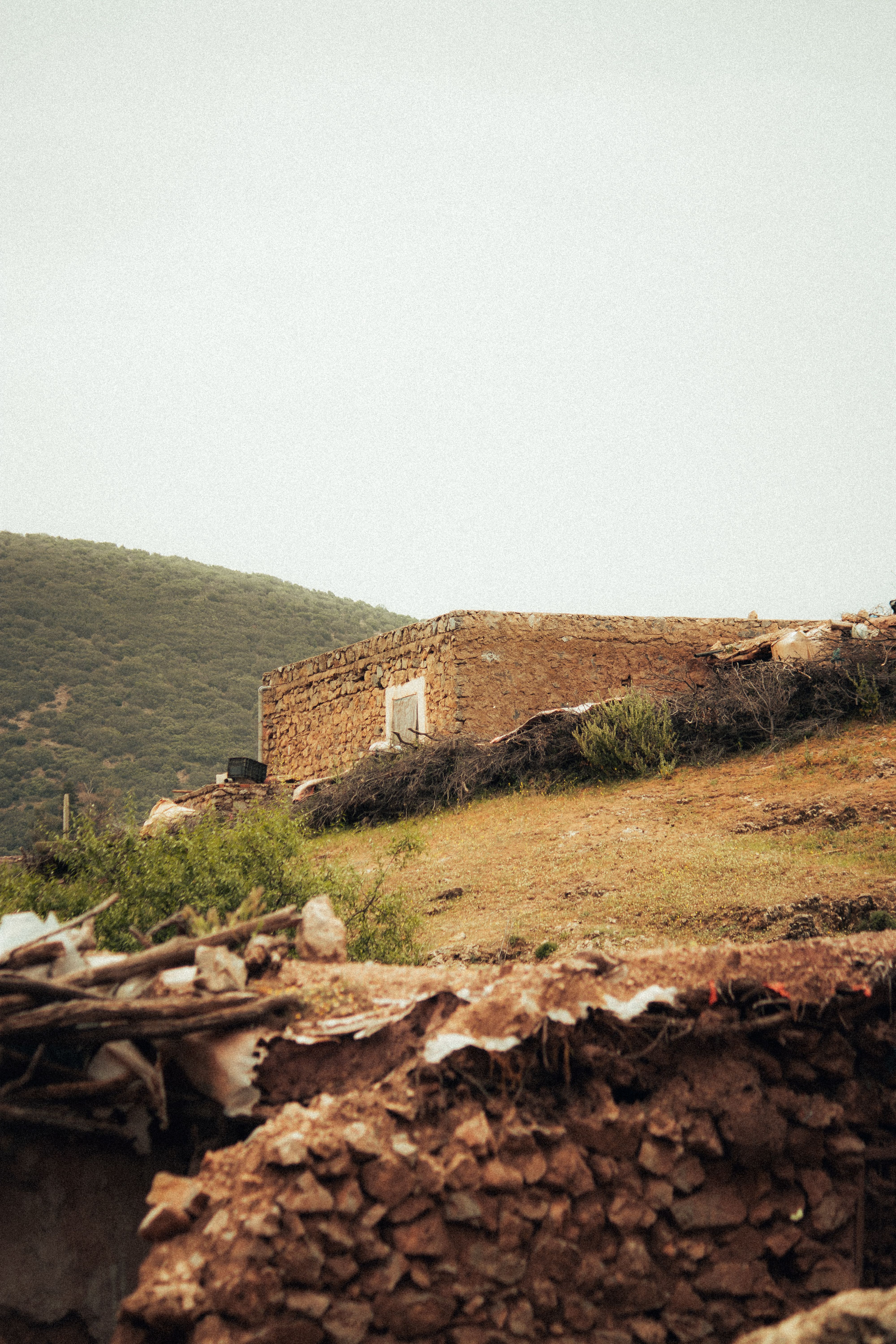 A solitary stone building amidst lush hills, showcasing rustic architecture in a tranquil rural scene.
