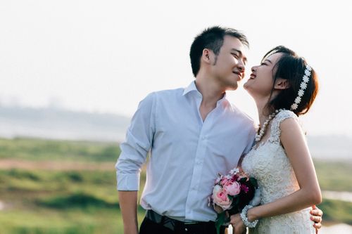 Free Couple embracing in a sunny outdoor wedding with a lush background in Hanoi, Vietnam. Stock Photo