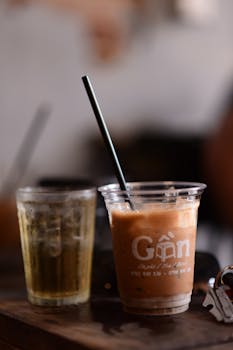 Refreshing iced coffee and green tea in plastic cups with rustic background, perfect for a chilled afternoon.