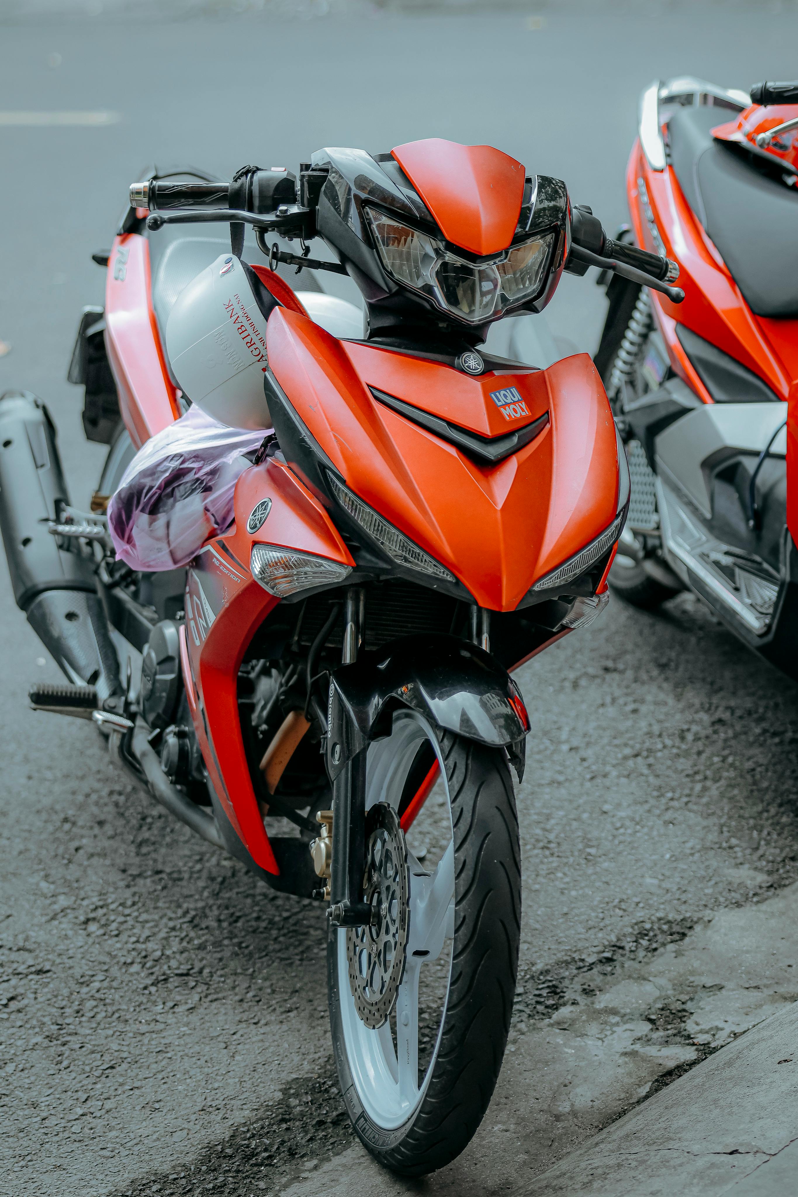 Free Close-up of a vibrant red motorcycle parked on an urban road, showcasing modern design. Stock Photo