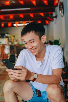 Happy man using a smartphone and smiling in a cozy indoor setting.