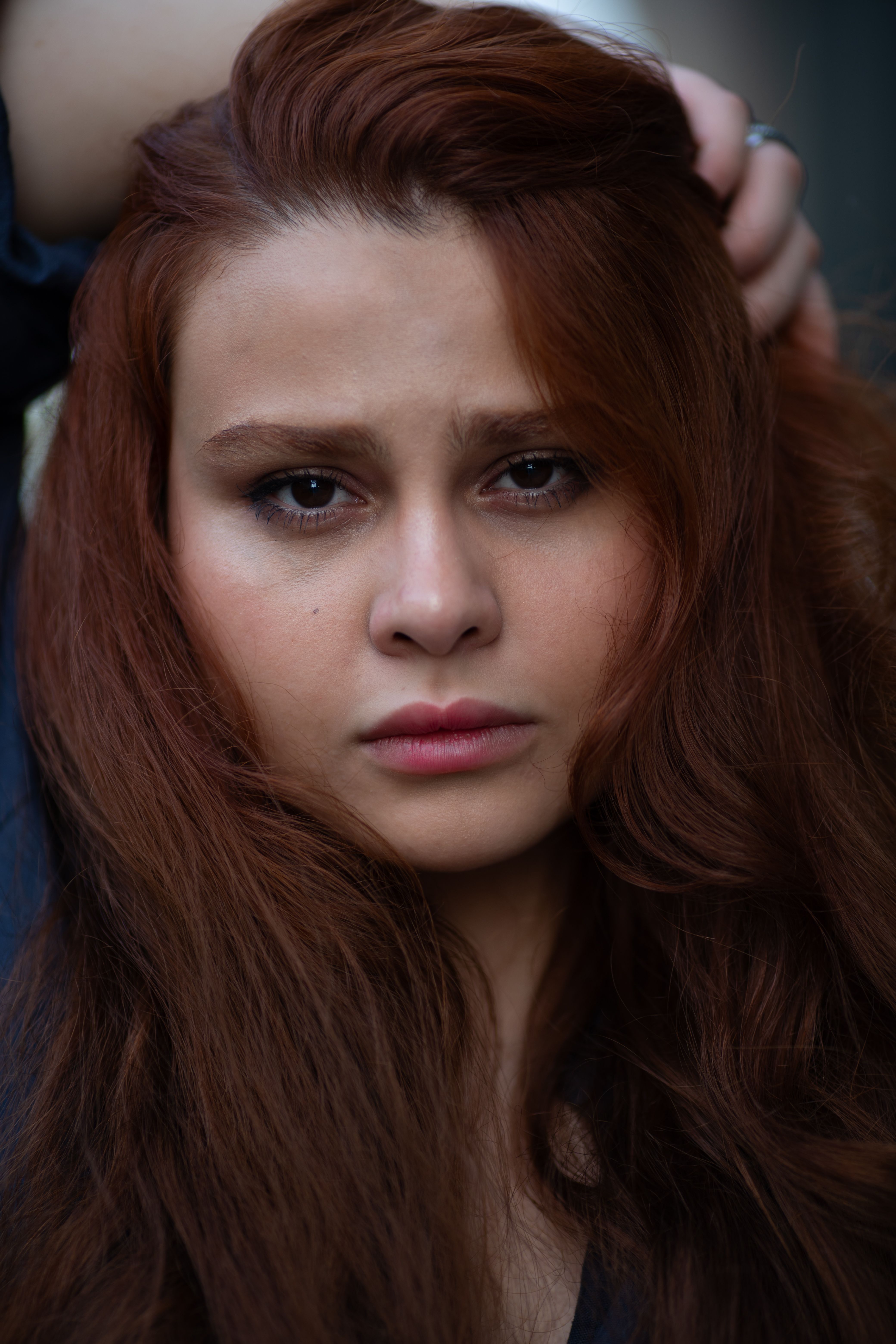 Close-up portrait of a young woman with auburn hair, capturing a pensive expression, shot in Baku.