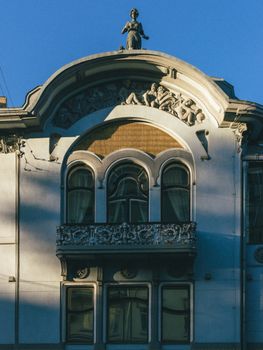 Art Nouveau building facade with ornate details and a statue rooftop at sunset.. nouveau, building, facade
