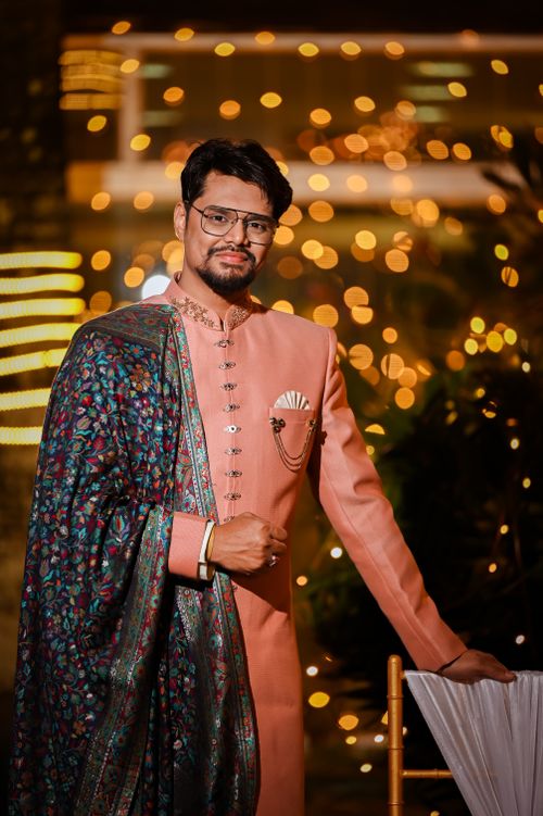 Free Man in traditional pink outfit with floral shawl at a nighttime event with bokeh lights. Stock Photo
