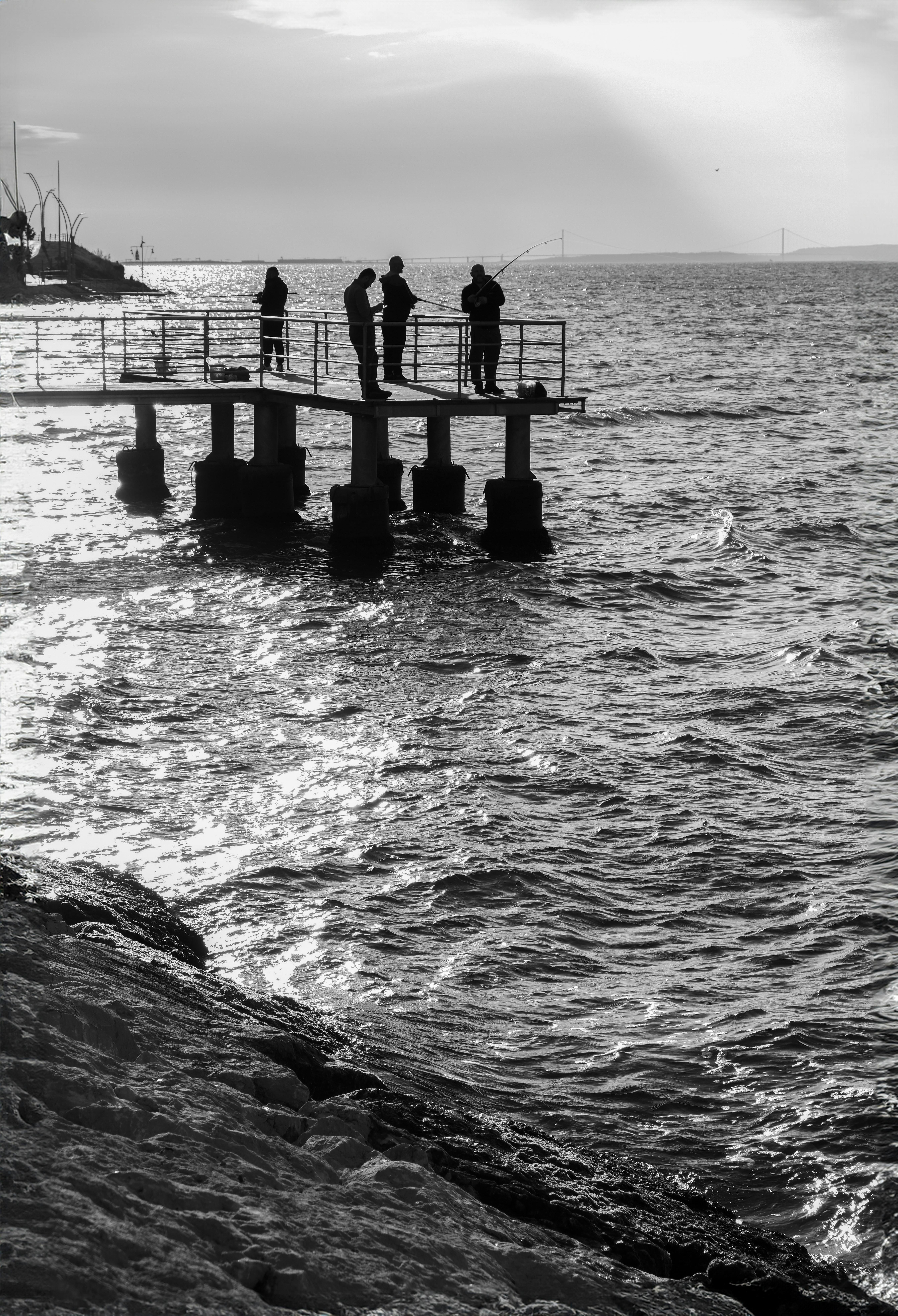 Silhouettes of people fishing on a pier in Degirmendere, Kocaeli during sunset.