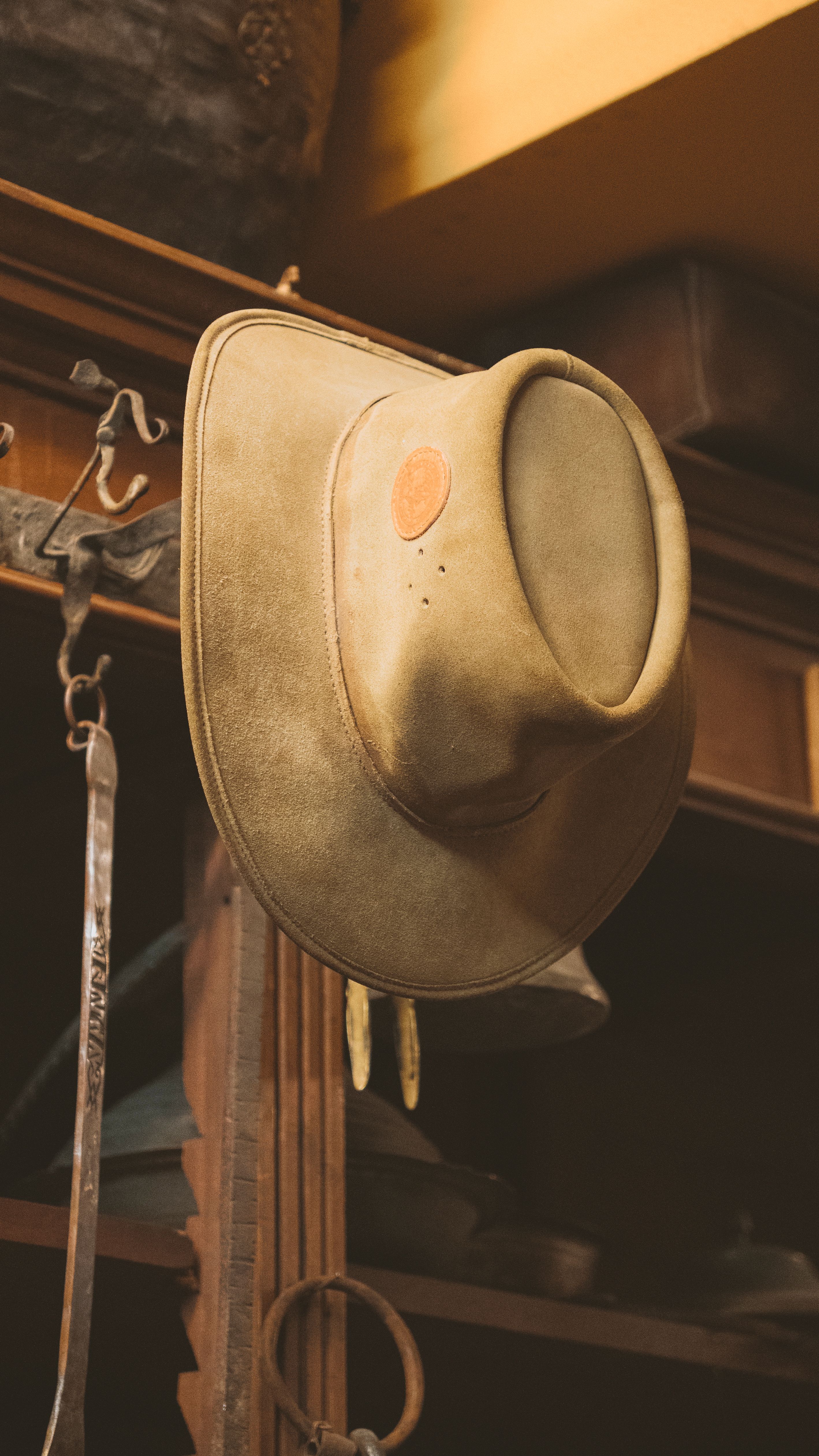 Old cowboy hat hung on a rustic wooden cabinet, evoking a vintage western atmosphere.