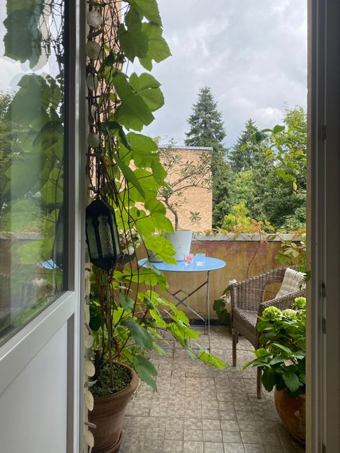 Inviting balcony view with plants, seating, and outdoor table, perfect for relaxation.