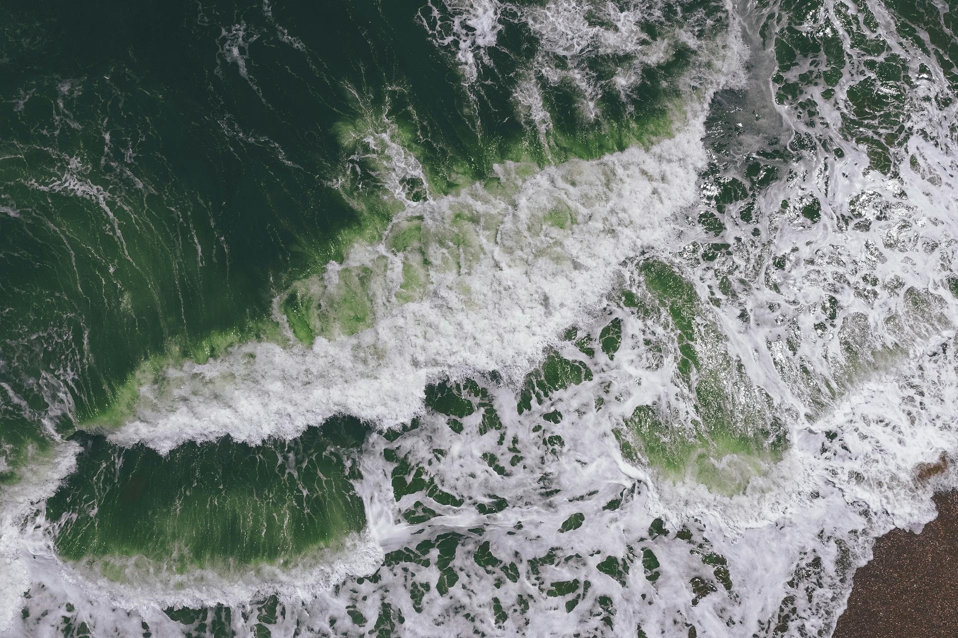 High-angle view capturing dynamic ocean waves and foam patterns in green hues.