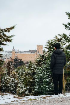 A person views the snowy landscape surrounding Alcázar of Segovia, Spain in winter.