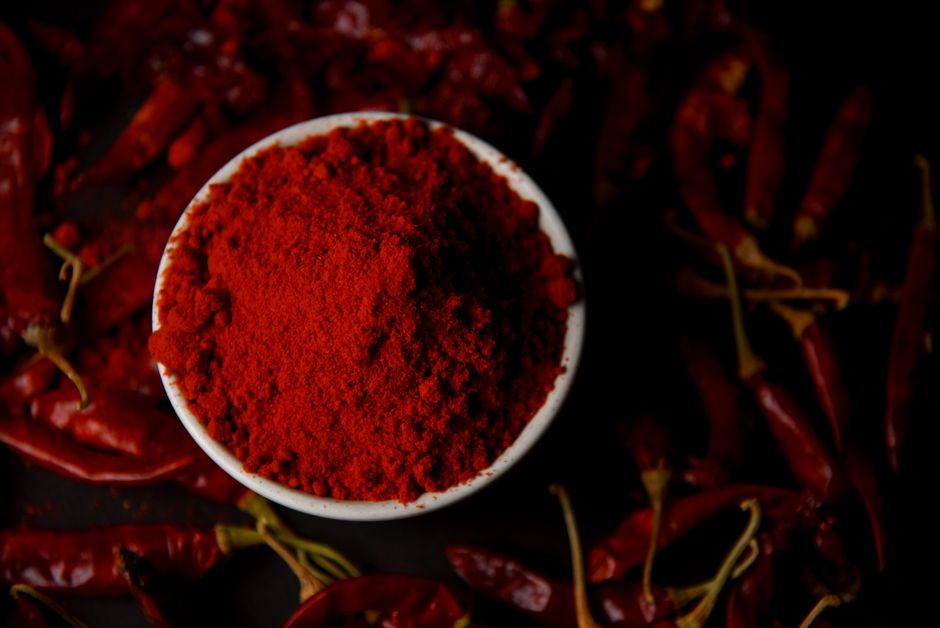 Pimentón rojo en polvo vertido sobre una superficie clara, mostrando su textura y color intenso