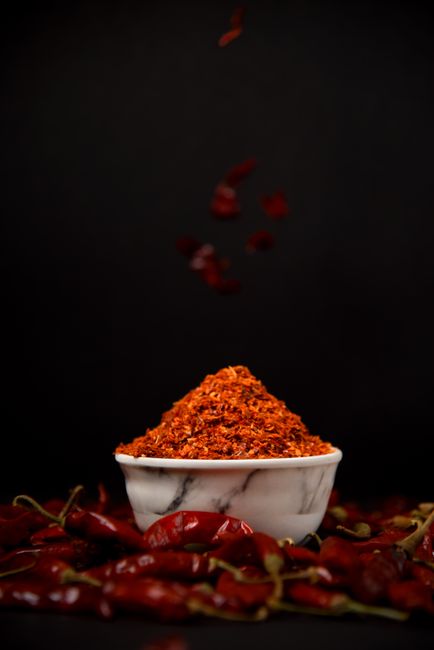 Bowl of bright red gochugaru chili flakes with whole dried chilis
