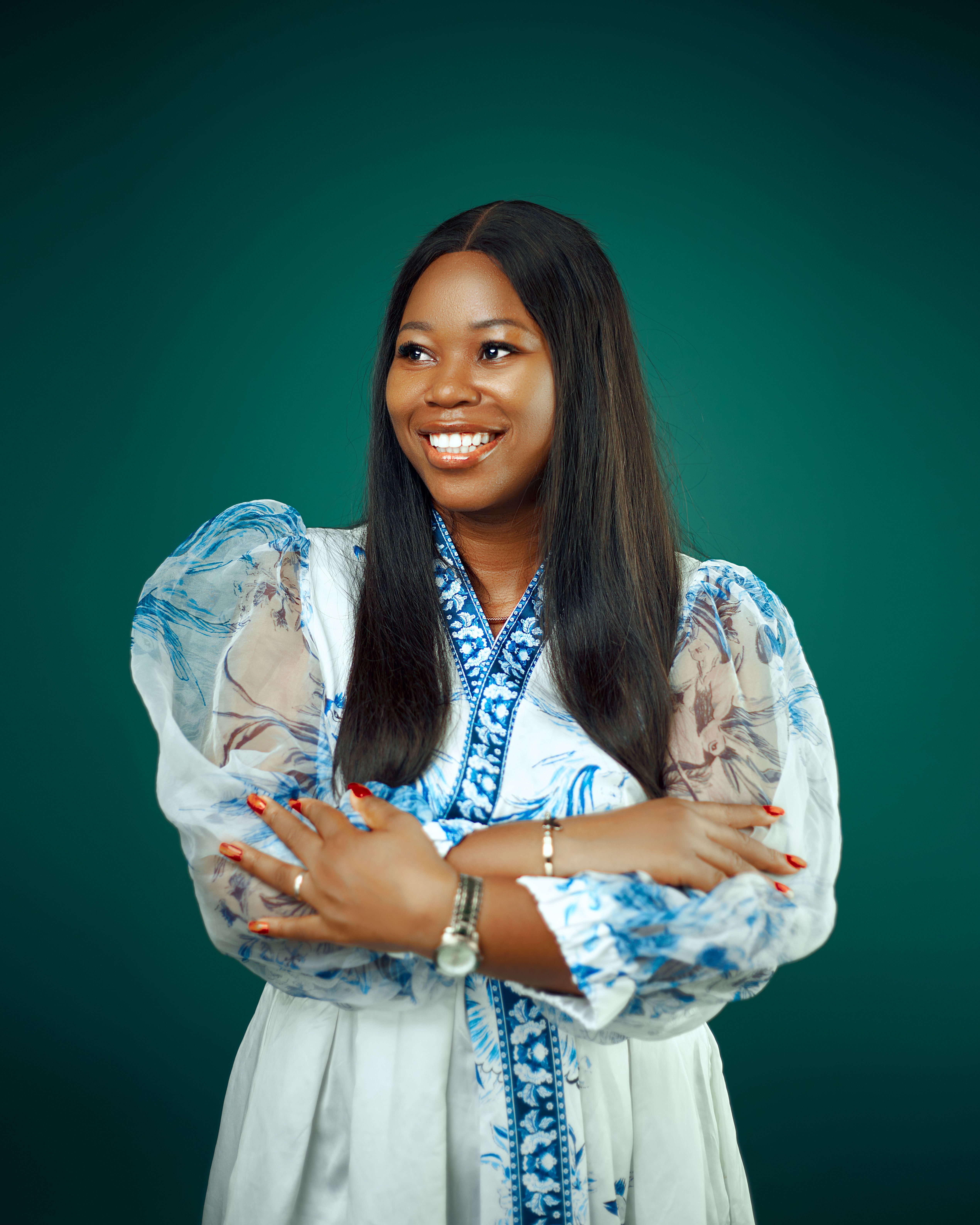 Portrait of a smiling woman in a fashionable dress against a green backdrop.