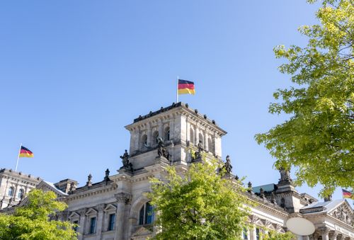 Free Reichstag Building in Berlin showcasing German flags on a sunny day. Stock Photo