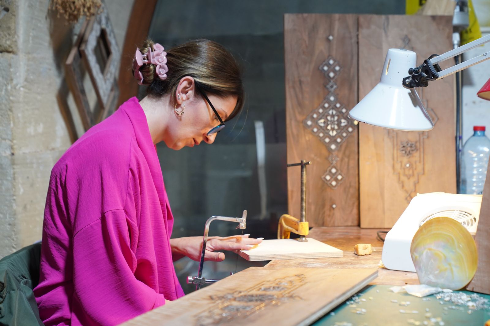 Female artisan focused on woodworking project in well-lit studio environment.