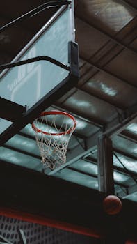 Dynamic shot of a basketball hoop with ball mid-air in an indoor court setting.