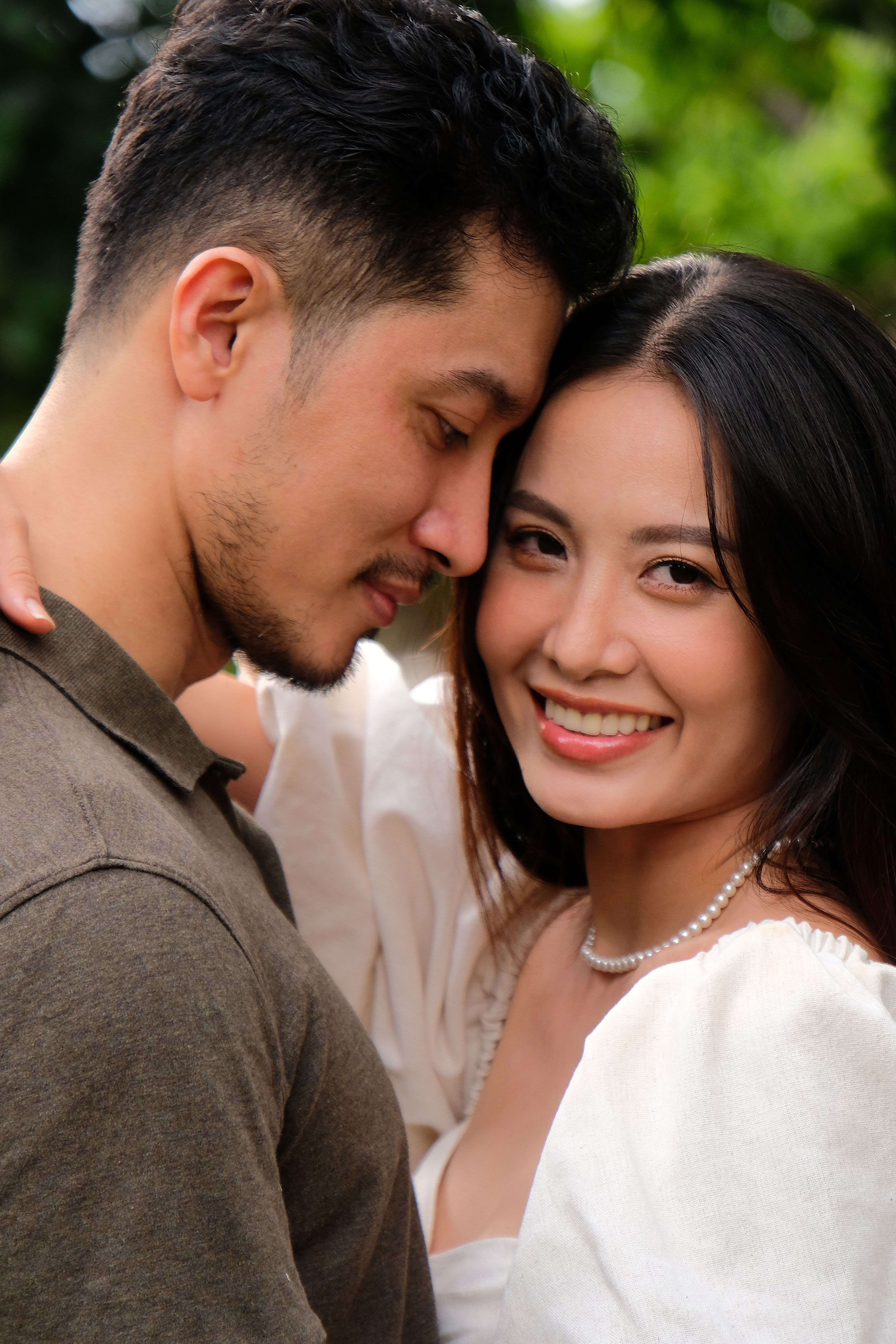 Happy couple embracing in a lush outdoor setting in Hồ Chí Minh City, Vietnam.