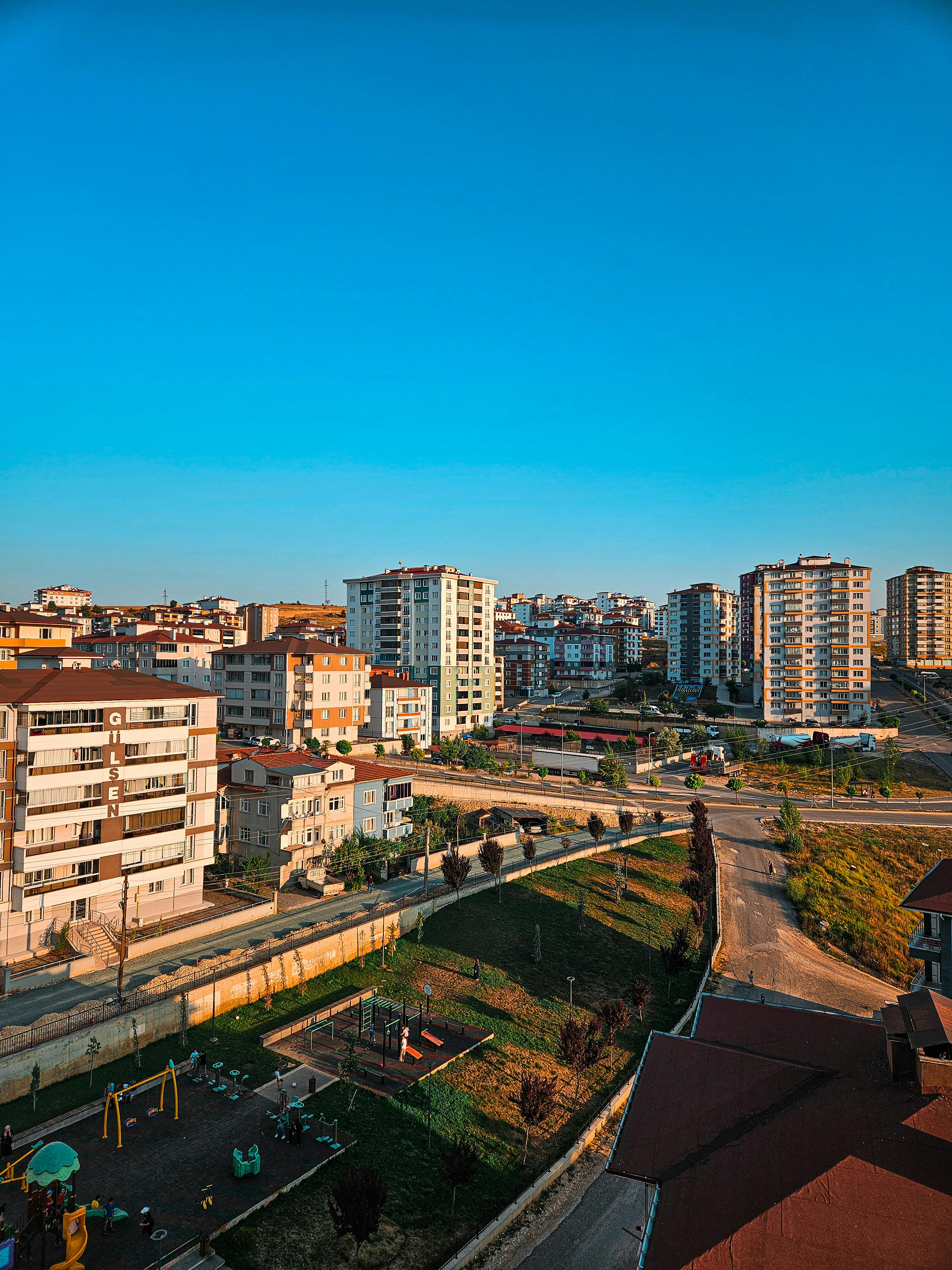 Aerial view of a sunny urban neighborhood with residential high-rise buildings and playground.