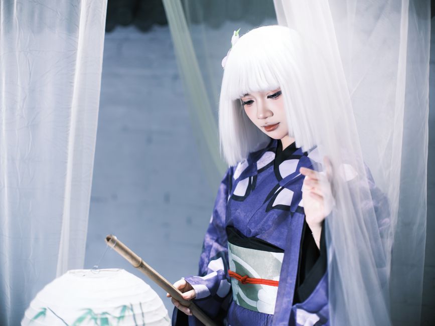 Beautifully styled cosplayer wearing traditional Japanese attire indoors, in a serene setting.