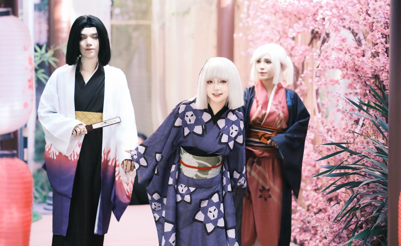 a group of cosplayers in traditional attire pose among cherry blossoms