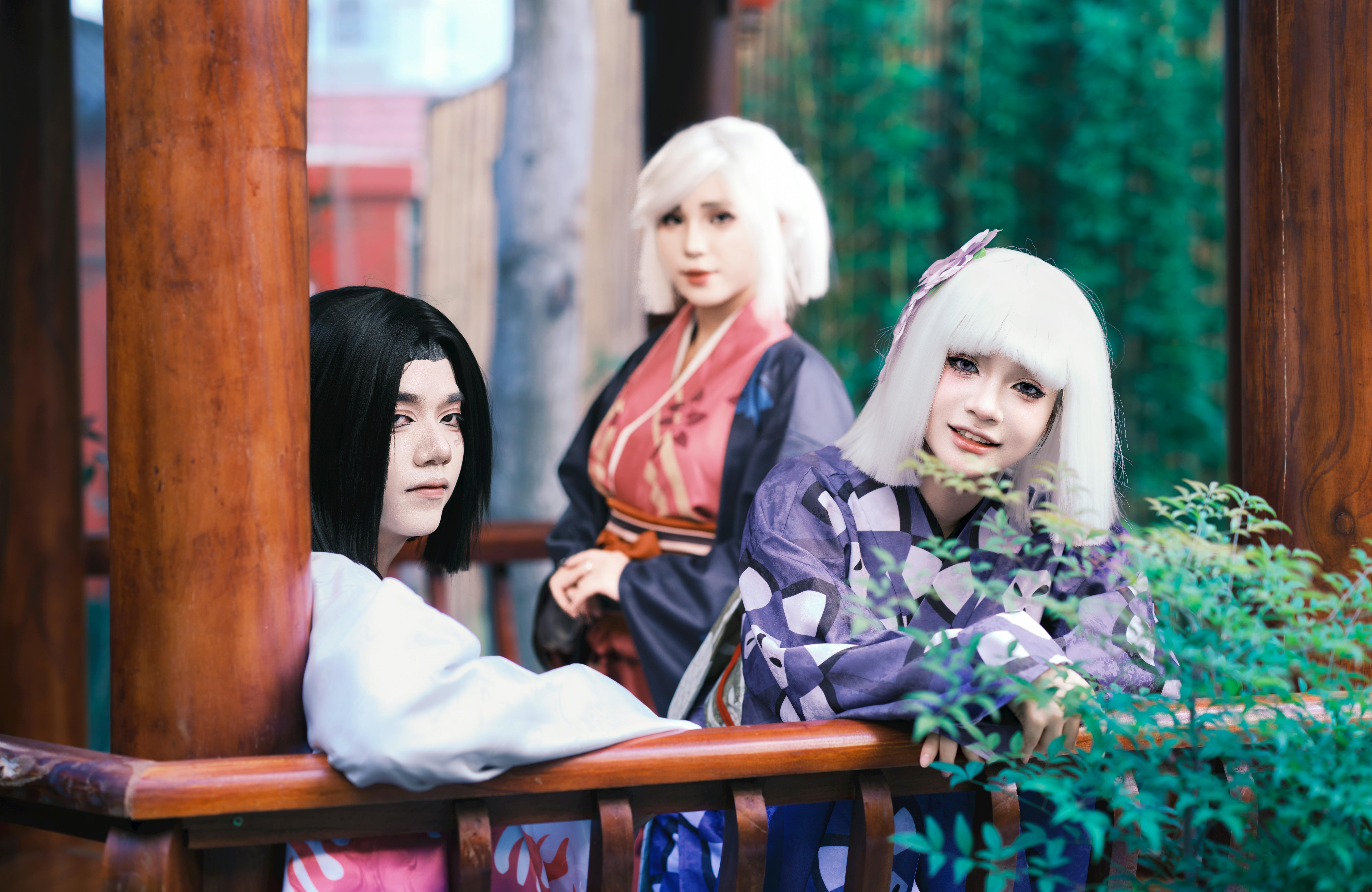 Three adults in colorful cosplay costumes pose outdoors, capturing a vibrant and artistic scene.