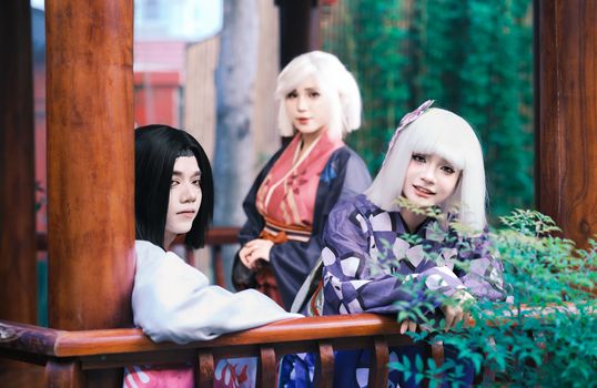 Three adults in colorful cosplay costumes pose outdoors, capturing a vibrant and artistic scene.