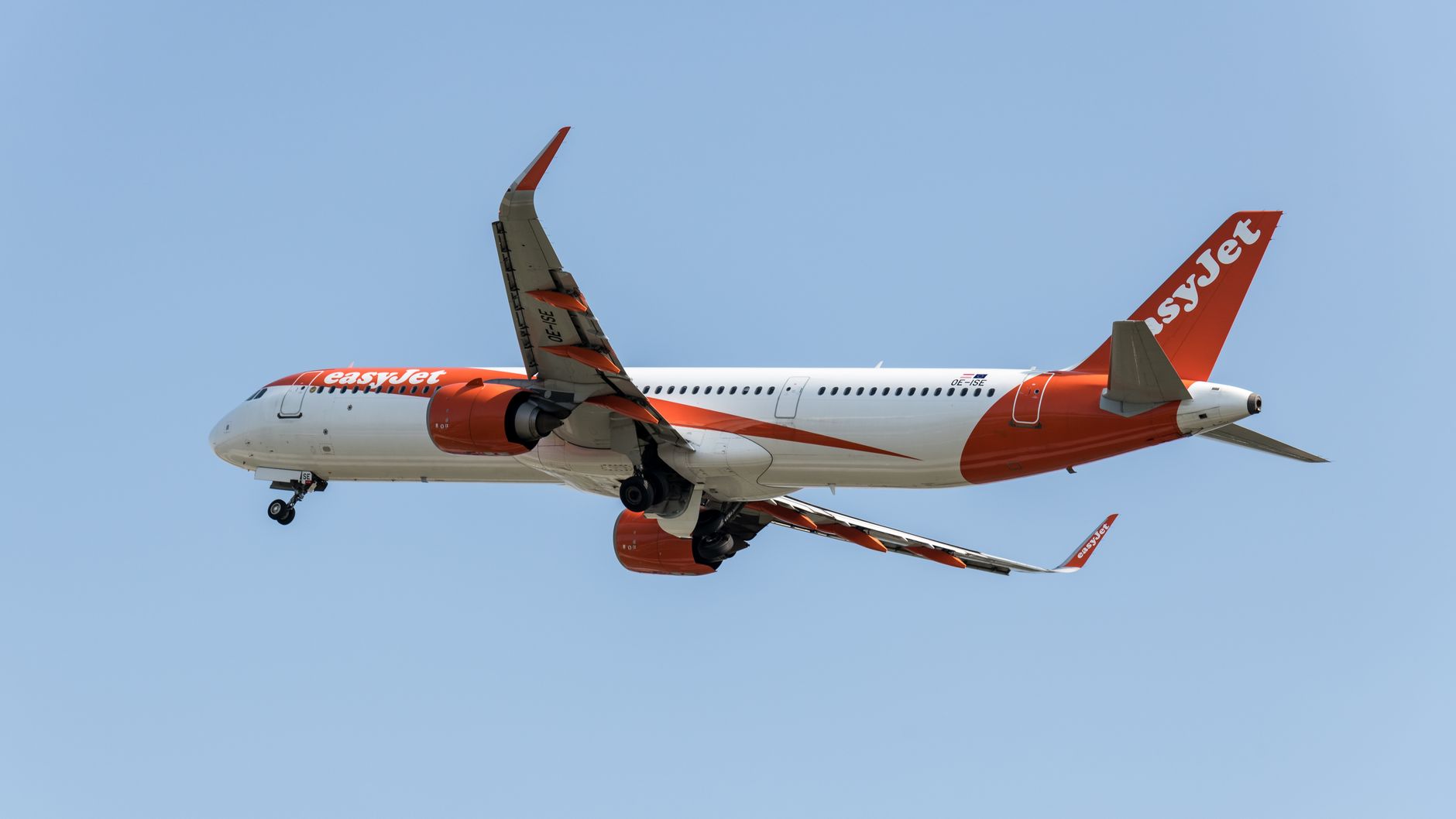 EasyJet aircraft flying above Prague during daytime, showcasing modern aviation in Europe.
