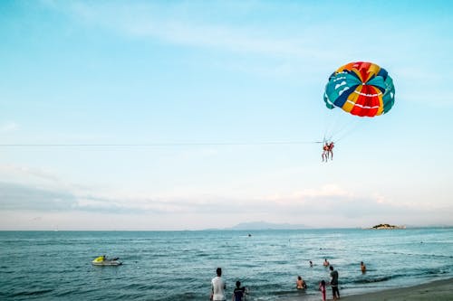 Person Riding Parachute Above Ocean
