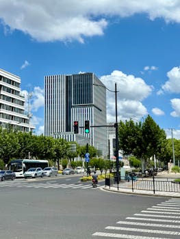 A vibrant city intersection featuring modern skyscrapers under a bright blue sky.