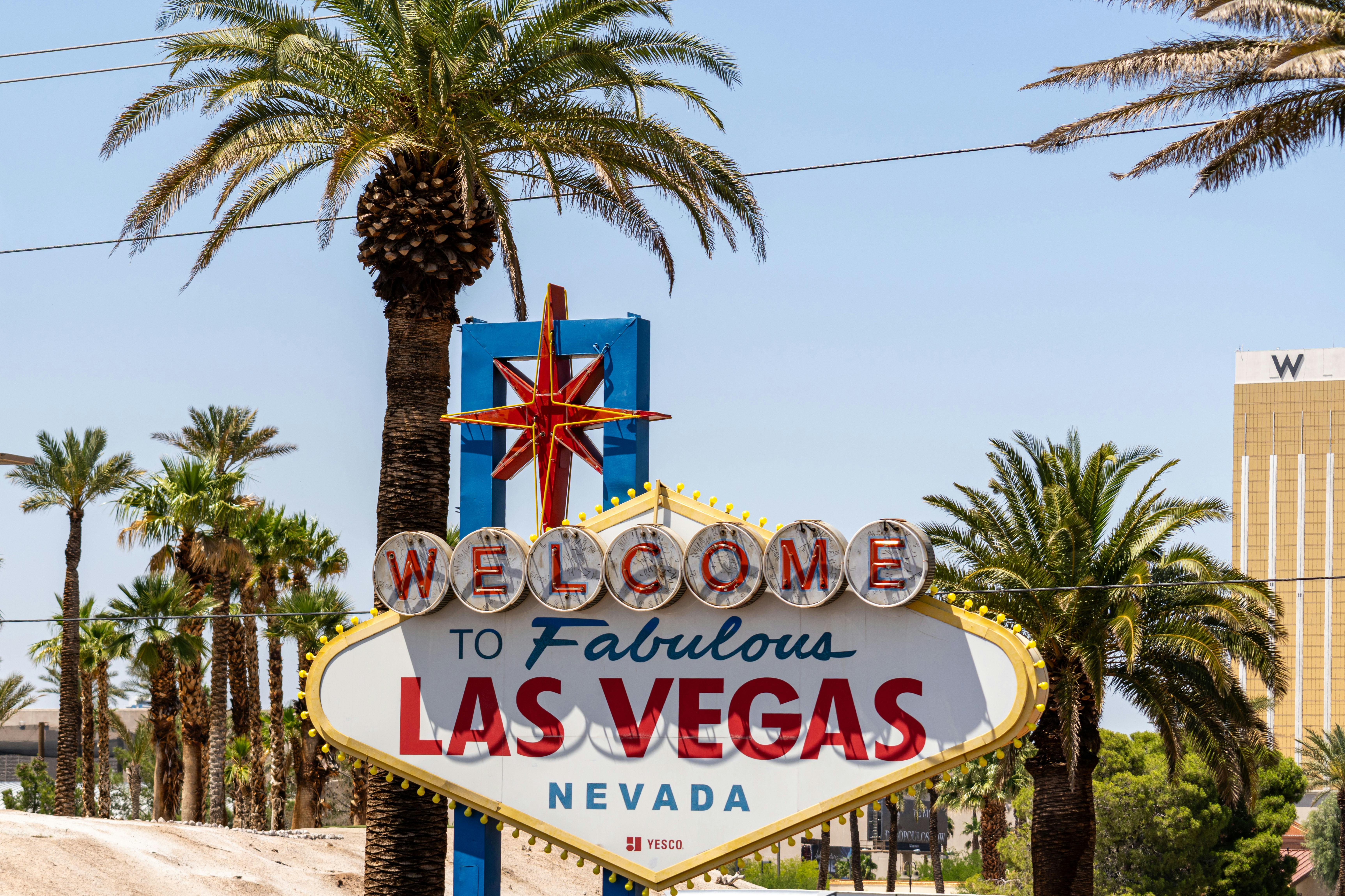 Free The classic 'Welcome to Las Vegas' sign amidst palm trees, under a bright blue sky. Stock Photo