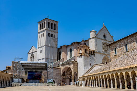 Explore the majestic Basilica of San Francesco in Assisi, Italy, under a clear blue sky.