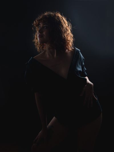 Low-light portrait of a woman with curly hair, photo by Eric Moura on Pexels