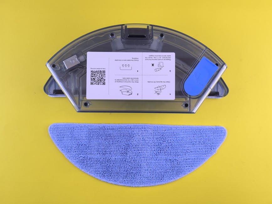 Best Robot Vacuums for Every Budget and Need (2025 Complete Guide) Cleaning robot water tank and mop on yellow backdrop, showcasing household appliance detail.