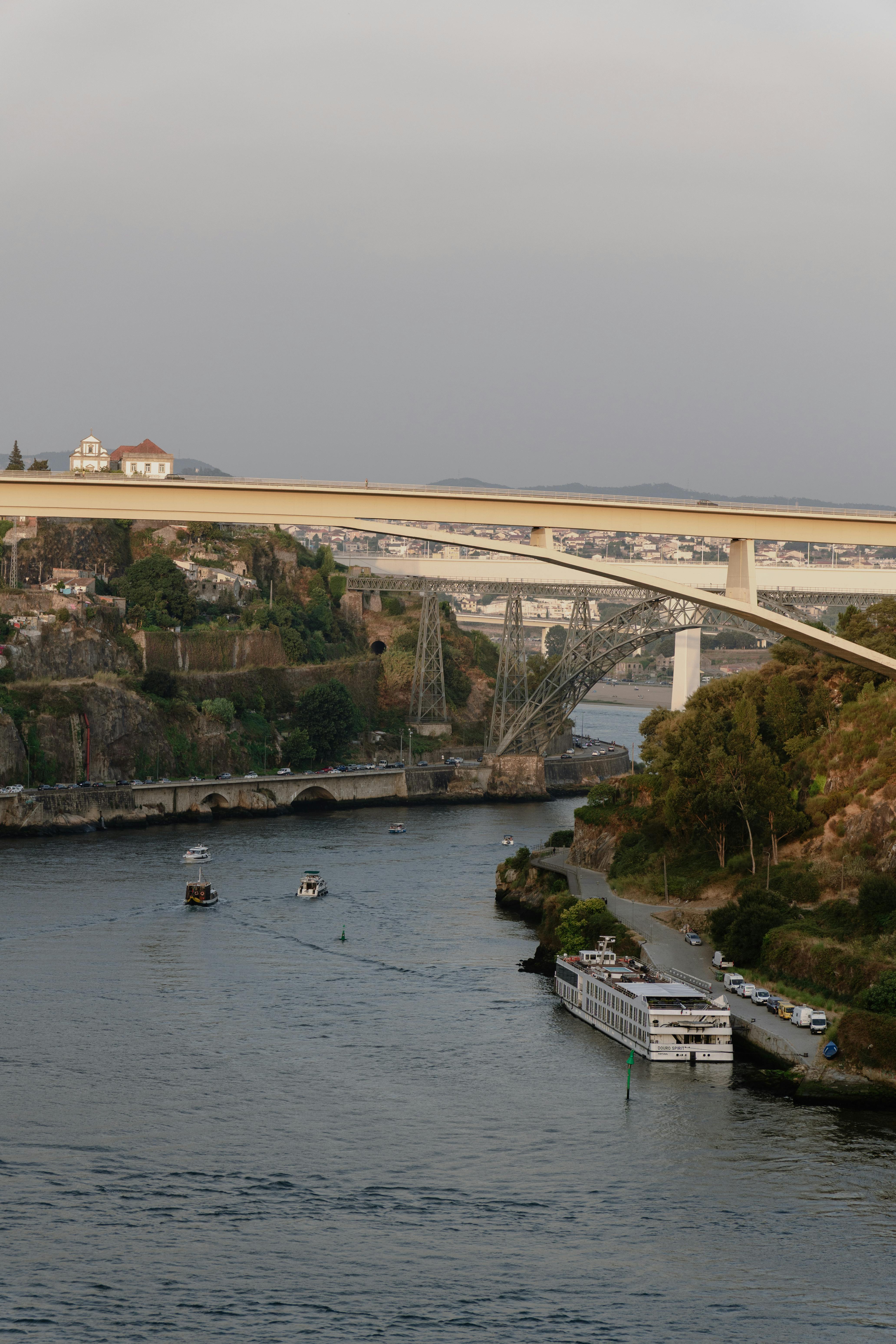 A picturesque view of the Douro River with boats and a bridge at sunset in Porto, Portugal.