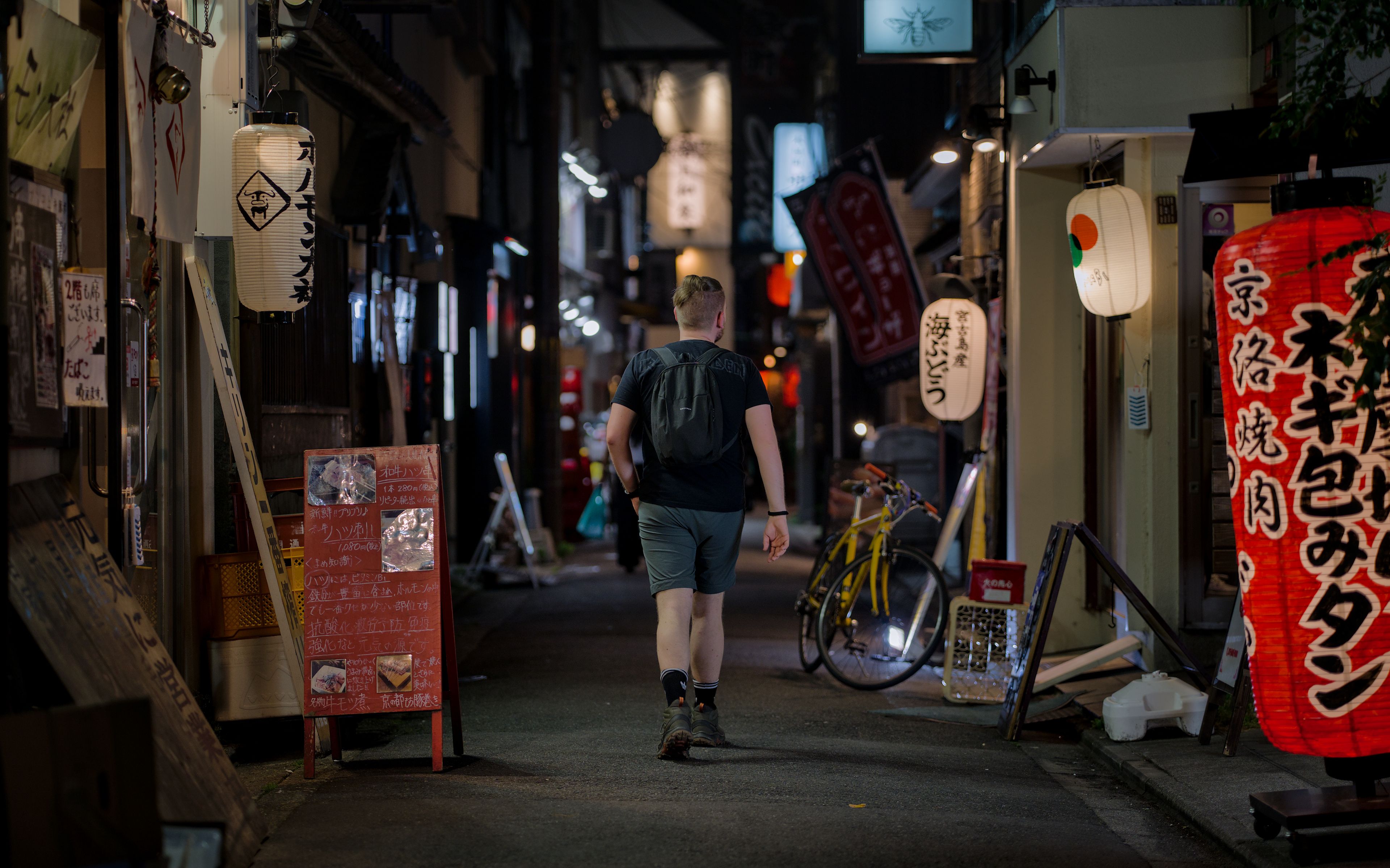A man walking through a traditional lantern-lit alley in Kyoto, Japan at night, capturing urban nightlife. A man walking through a traditional lantern-lit alley in Kyoto, Japan at night, capturing urban nightlife.
