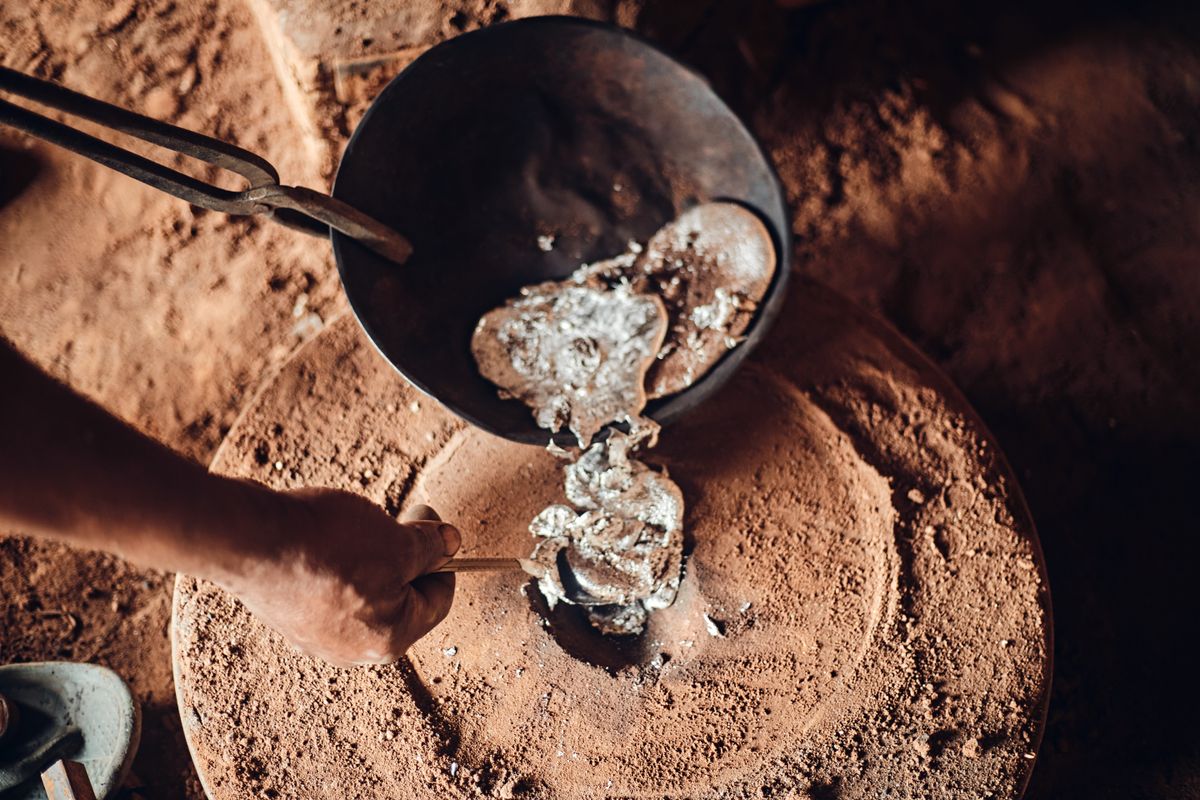Molten metal poured from a crucible in a sand foundry