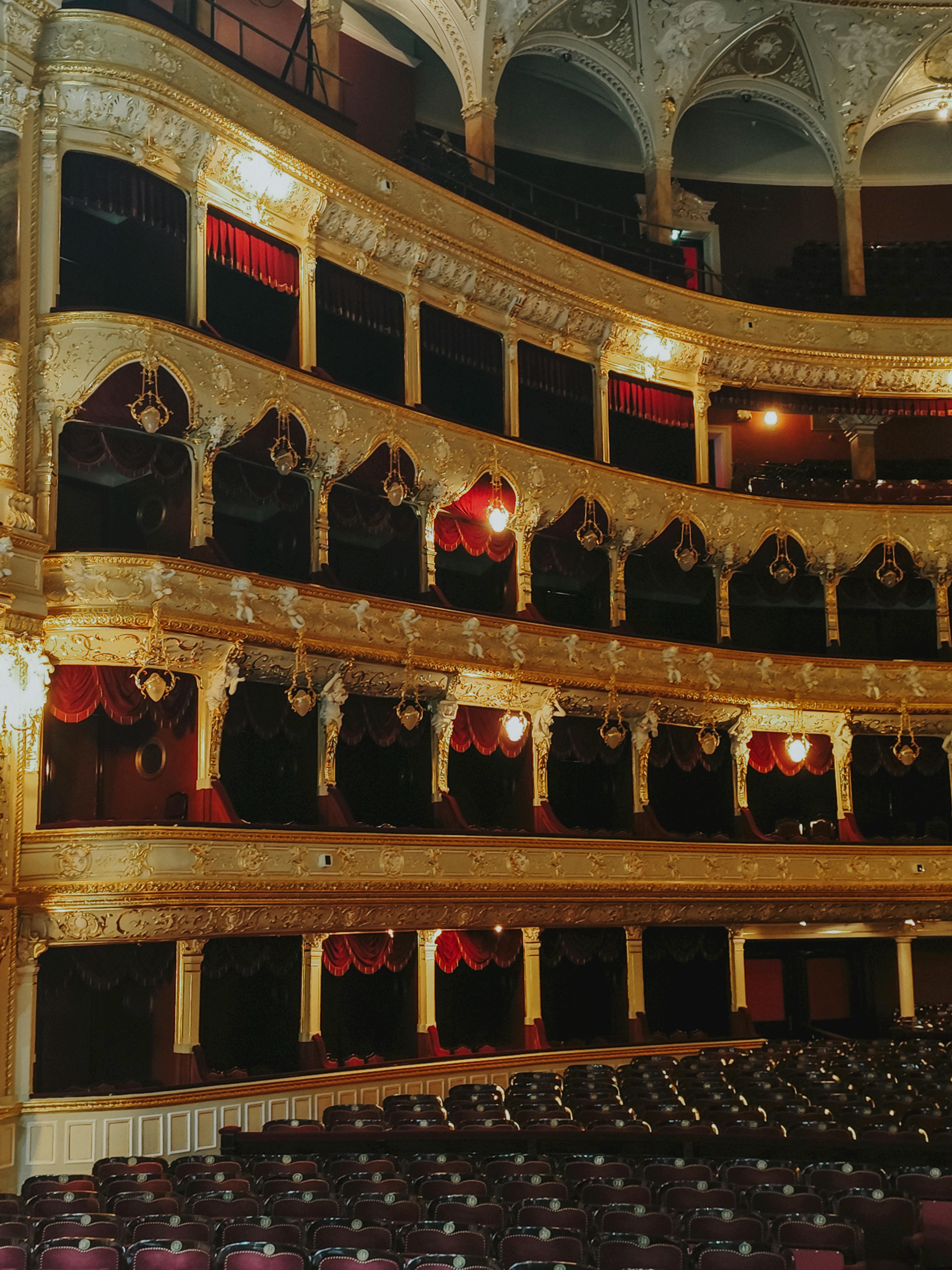 Free Luxurious opera house interior featuring ornate gold designs and red velvet balconies. Stock Photo