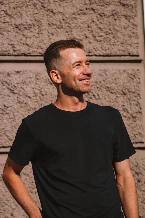 Free Casual portrait of a smiling man in sunlight against a textured wall. Stock Photo