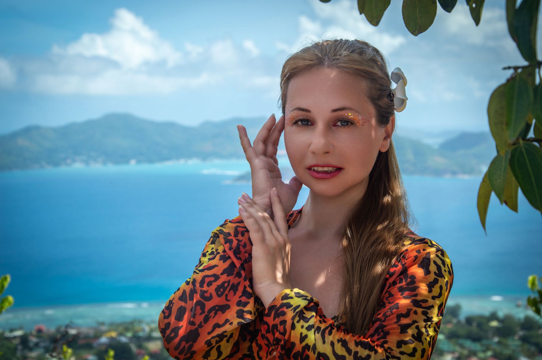 Portrait of a woman in leopard print with a stunning tropical ocean view.