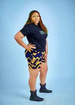 Confident woman in patterned skirt and black top posing against a blue backdrop.