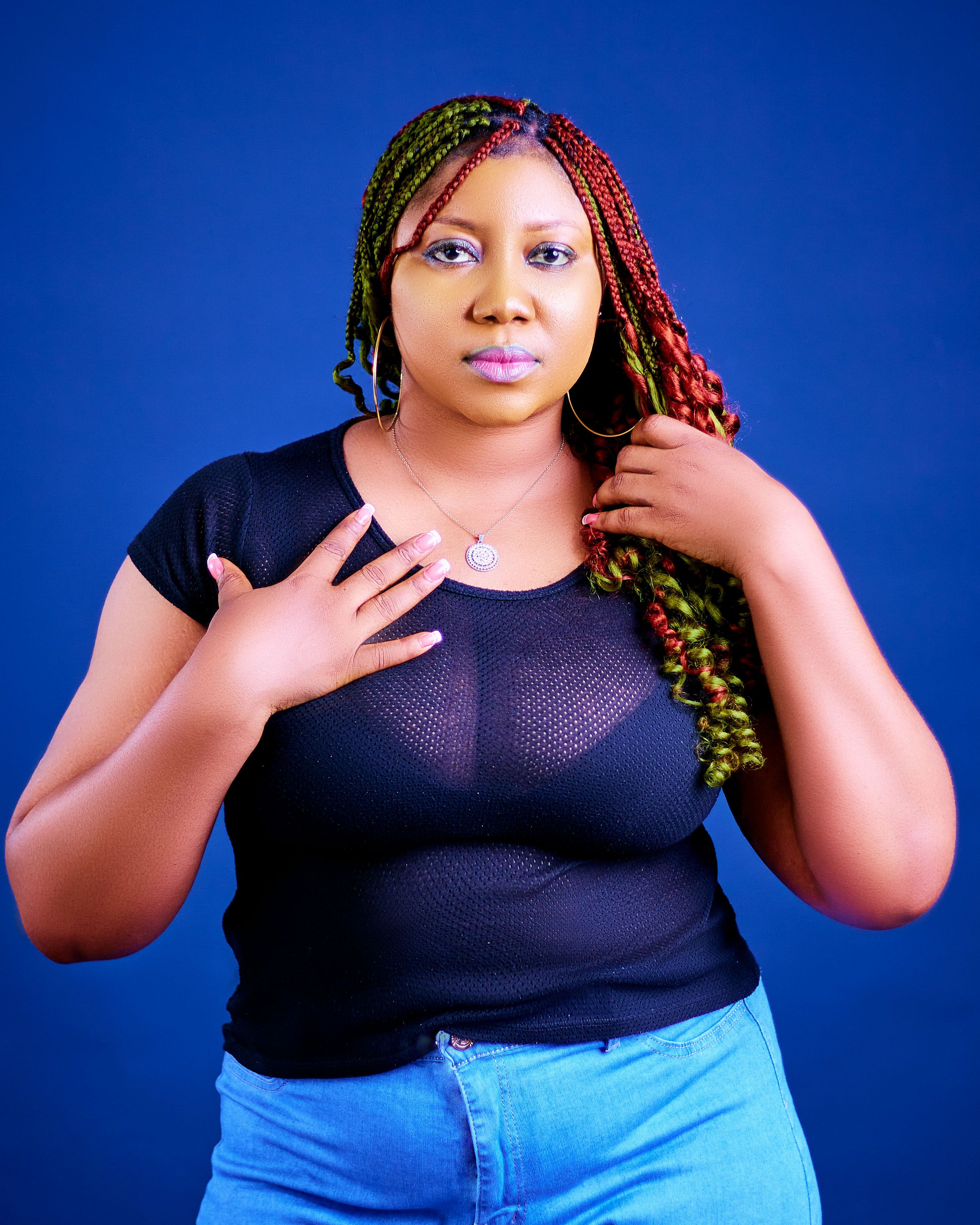 Vibrant portrait of a woman with colorful braided hair against a blue background.